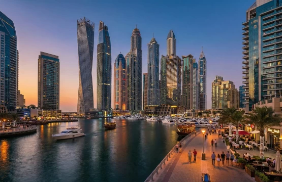 Illuminated skyscrapers and yachts in the Dubai Marina canal during twilight.